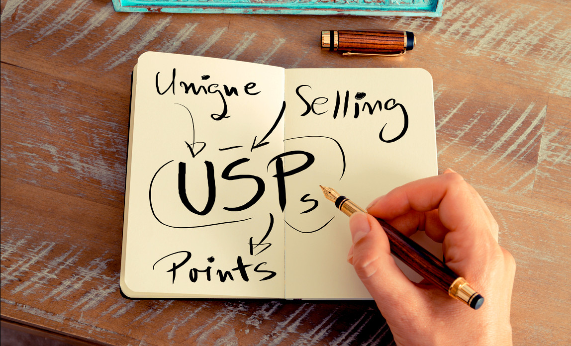 How to start a business - A person holding a pen with a notebook written “USP”